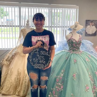 A woman is standing in front of a bunch of dresses in a store.