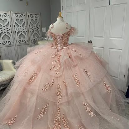 A pink ball gown is on a mannequin in a room.