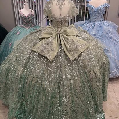 A green ball gown with a bow on the back is sitting on top of a mannequin.