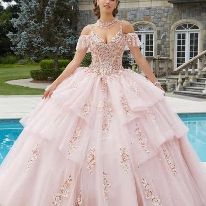 A woman in a pink ball gown is standing next to a pool.