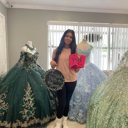 A woman is standing in front of a bunch of dresses in a store holding a sign.