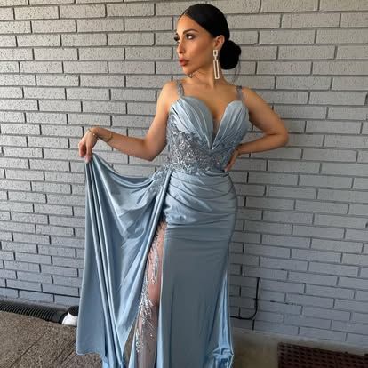 A woman in a blue dress is standing in front of a brick wall