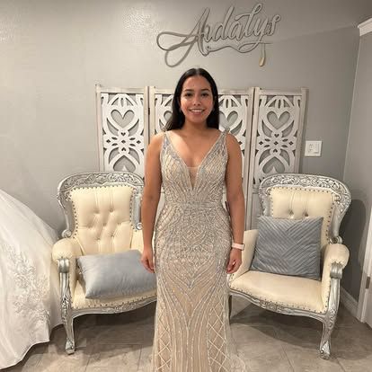 A woman in a long dress is standing in a room with chairs.