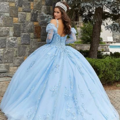 A woman is wearing a light blue ball gown and a tiara.