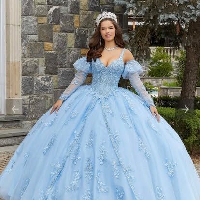 A woman is wearing a light blue ball gown and a tiara.