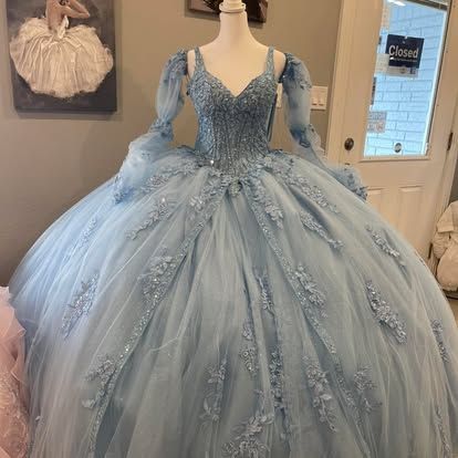 A light blue ball gown is on a mannequin in a room.