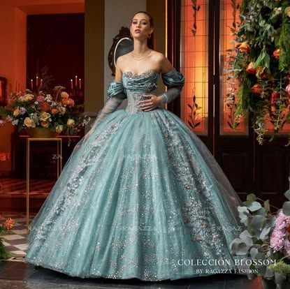 A woman in a blue ball gown is standing in front of flowers.