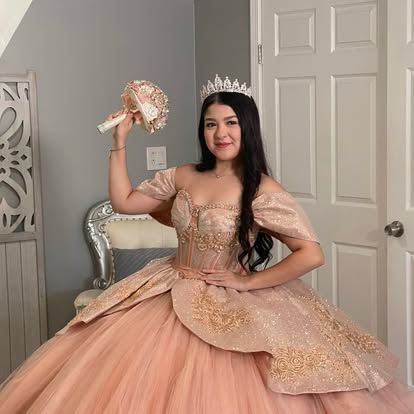 A woman in a pink ball gown and tiara is holding a bouquet of flowers.