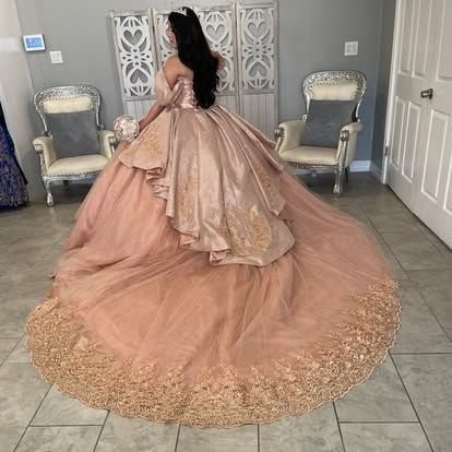 A woman is wearing a long pink and gold ball gown.