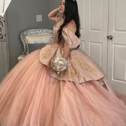 A woman in a pink ball gown is holding a bouquet of flowers.