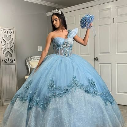 A woman is wearing a light blue ball gown and holding a bouquet of flowers.