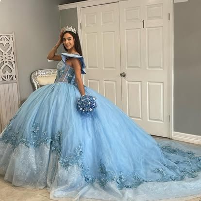 A woman is wearing a light blue ball gown and holding a bouquet of flowers.