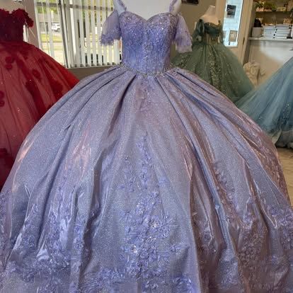 A purple ball gown is on a mannequin in a store.