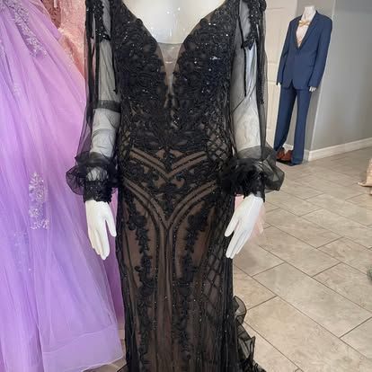 A black dress is on a mannequin in a store.