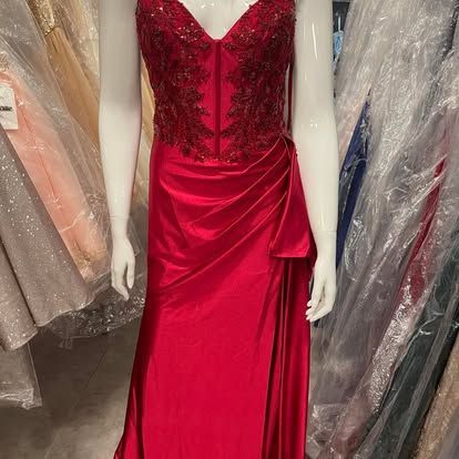 A red dress is on a mannequin in a store.