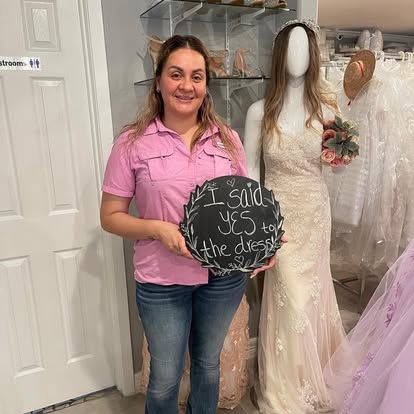 A woman is holding a sign that says `` i said yes to the dress '' in front of a mannequin.