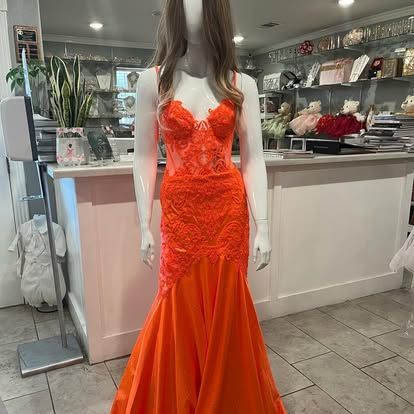 A mannequin is wearing an orange dress in a store.