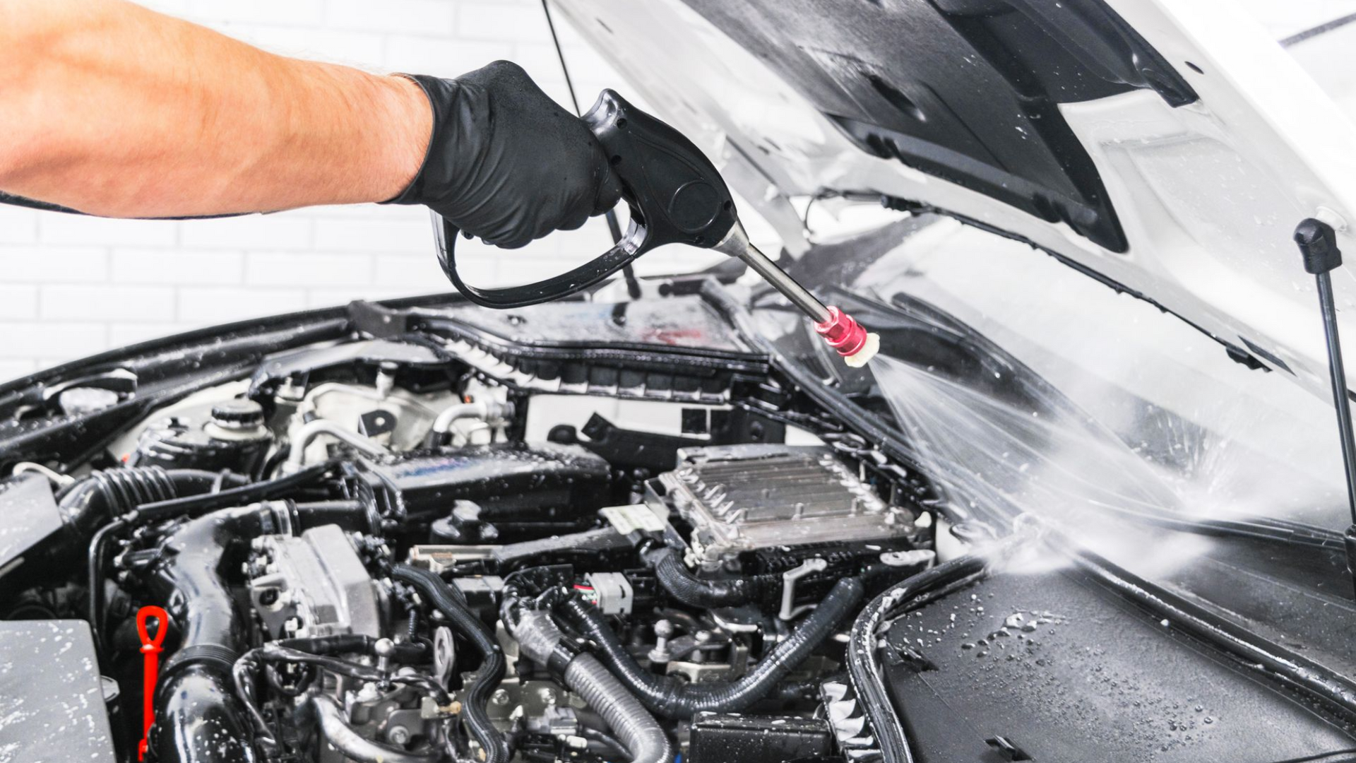 A man is cleaning the engine of a car with a towel.