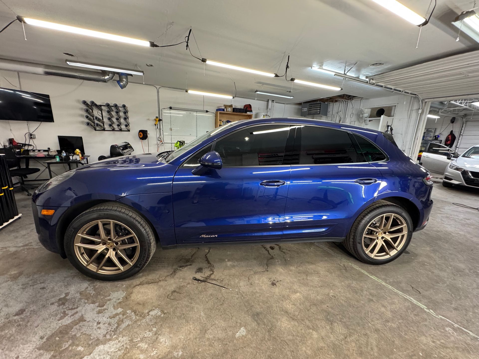 Blue Porsche SUV with tinted windows and gold rims inside a garage.