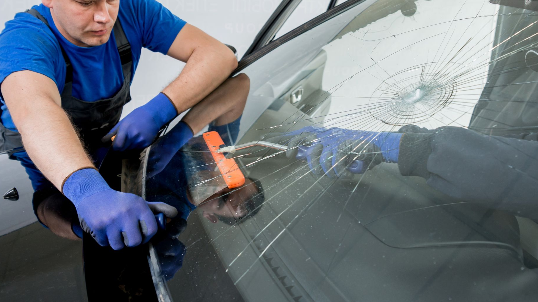 A man is cleaning the engine of a car with a towel.