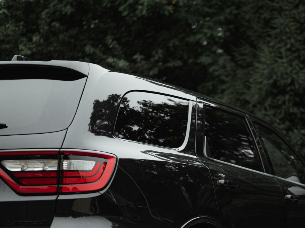 A man is cleaning the engine of a car with a towel.