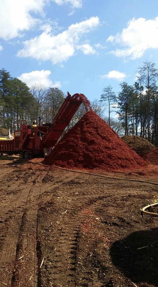 A pile of red mulch is being loaded into a truck.