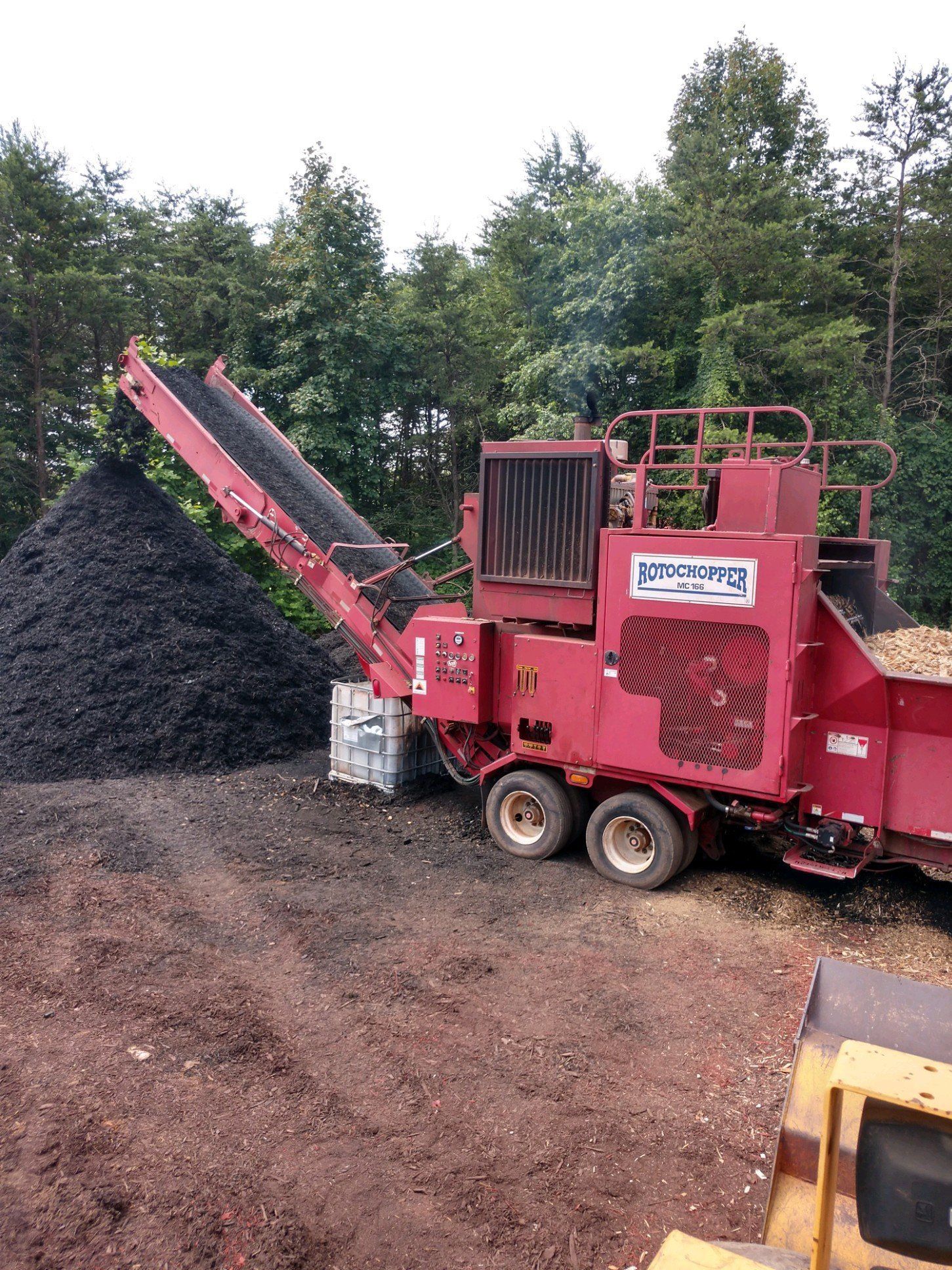 A red machine is sitting on top of a pile of dirt.