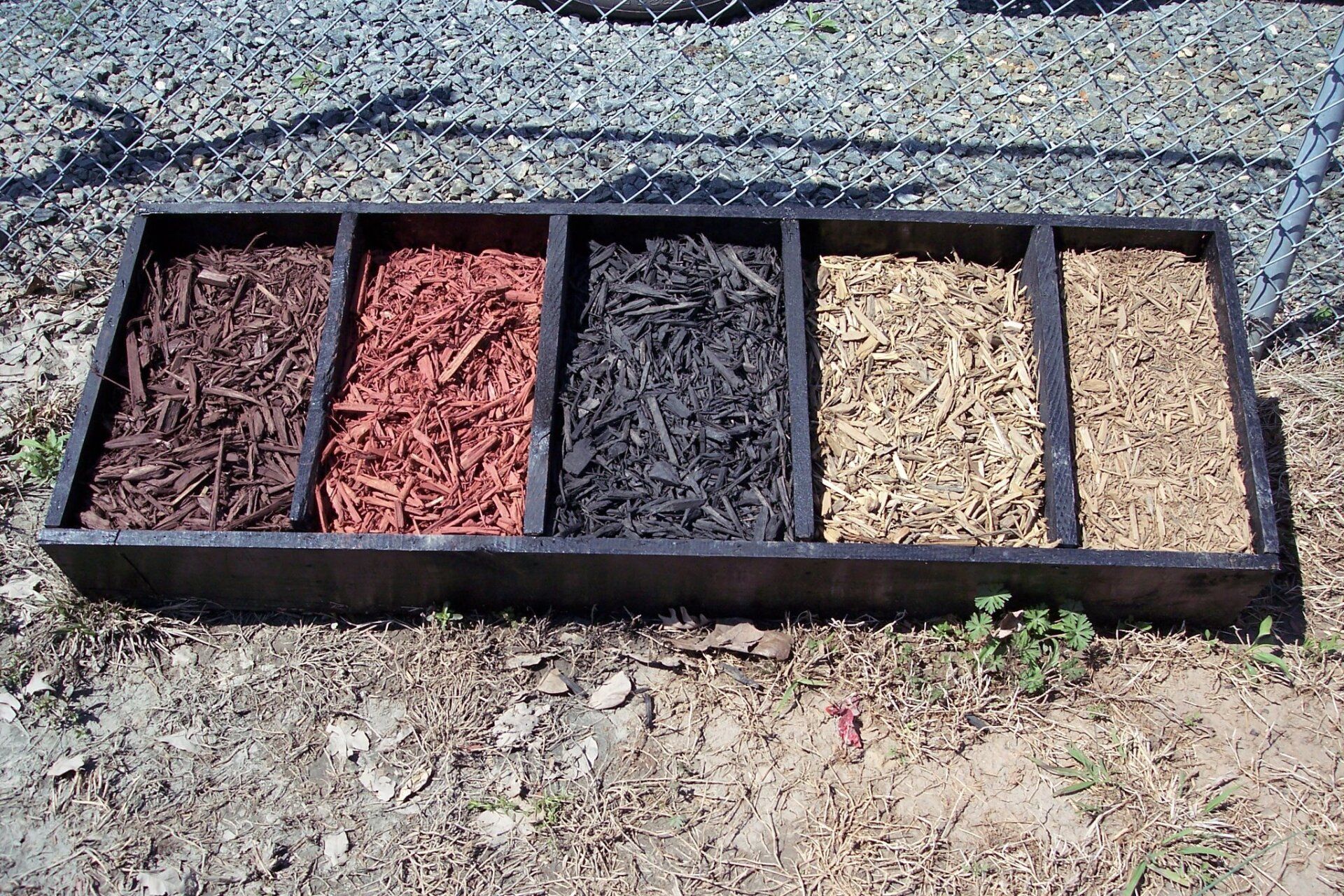 A wooden tray filled with different types of mulch
