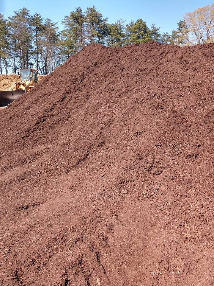 A large pile of brown dirt with trees in the background.