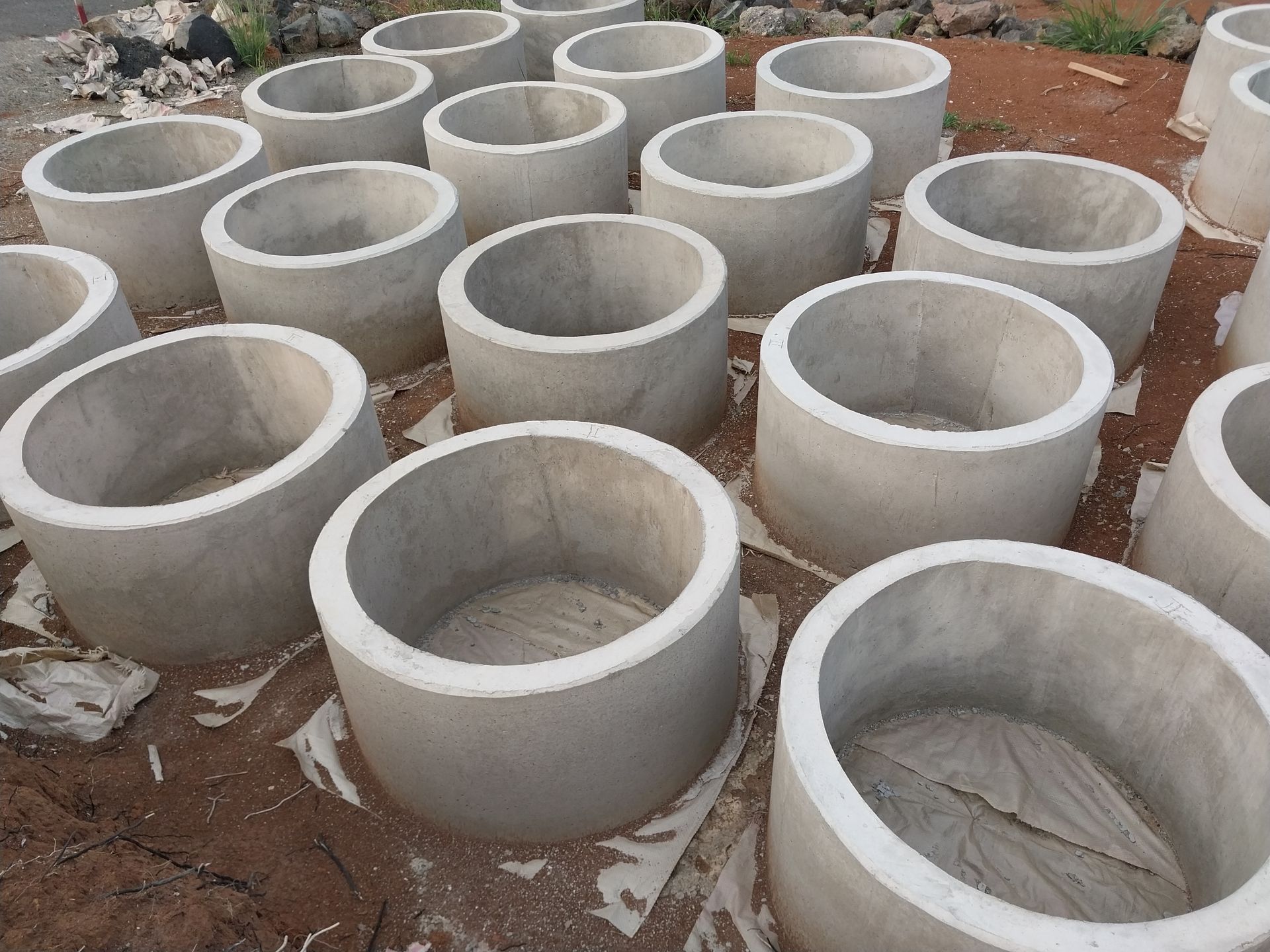 Concrete rings, likely for well construction, neatly arranged outdoors.