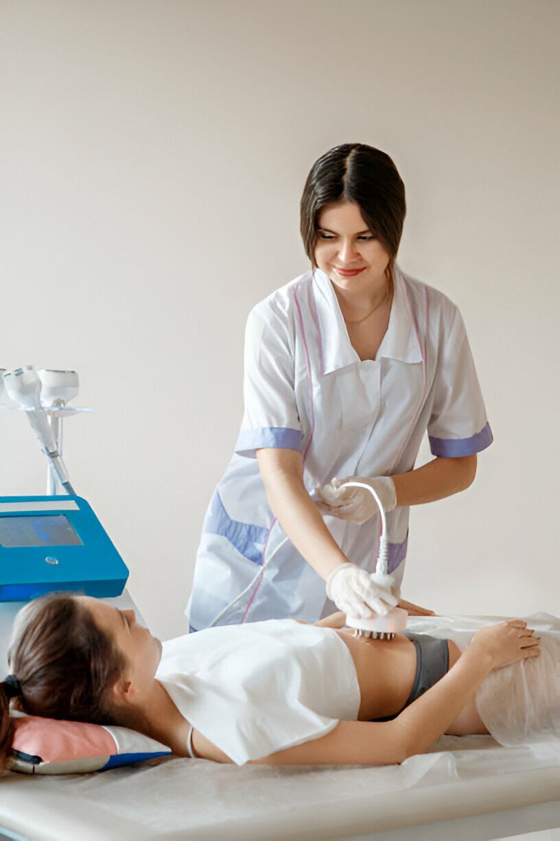 A medical professional using a device on a patient's abdomen in a treatment room.