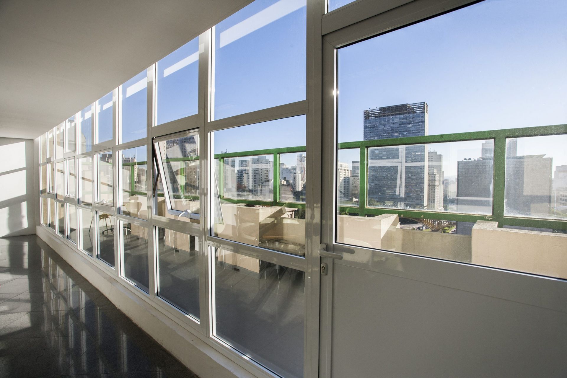 Um corredor com muitas janelas e vista para a cidade.