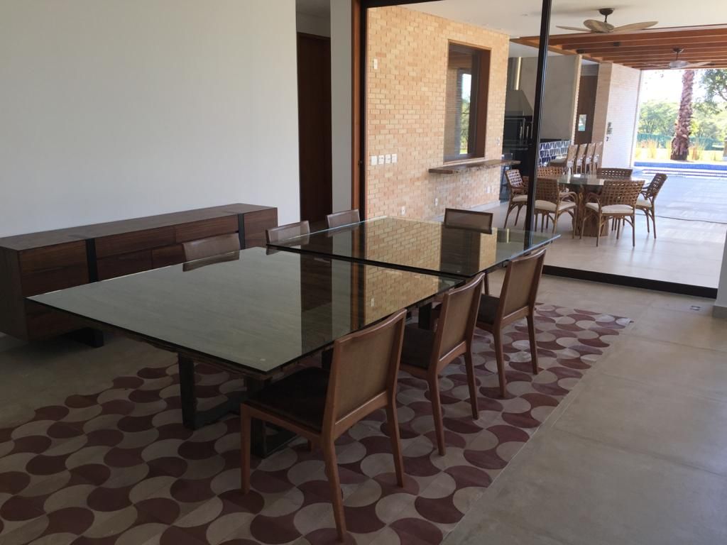 Uma sala de jantar com uma longa mesa de vidro e cadeiras