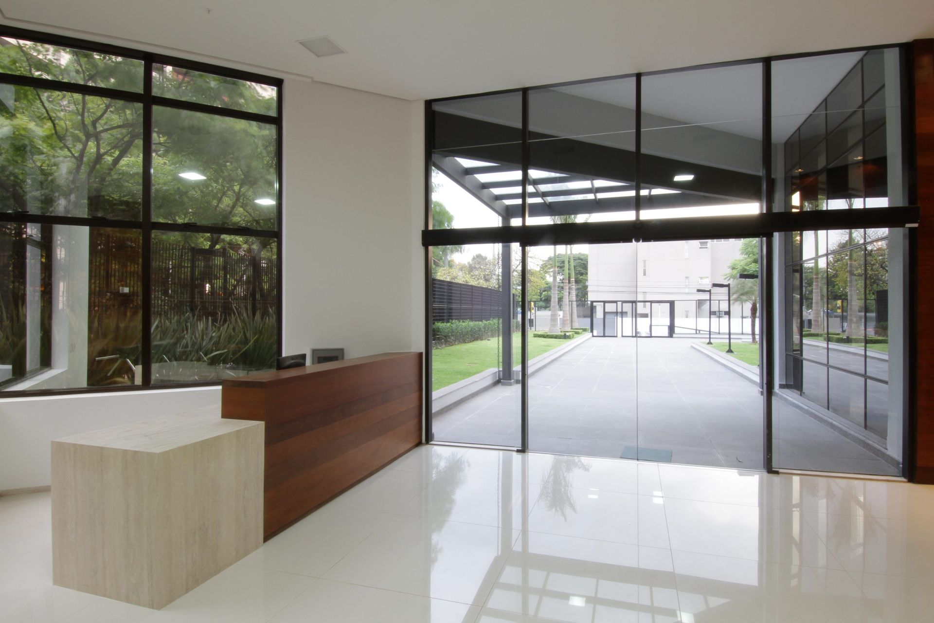 Um saguão vazio com uma mesa de madeira e grandes janelas