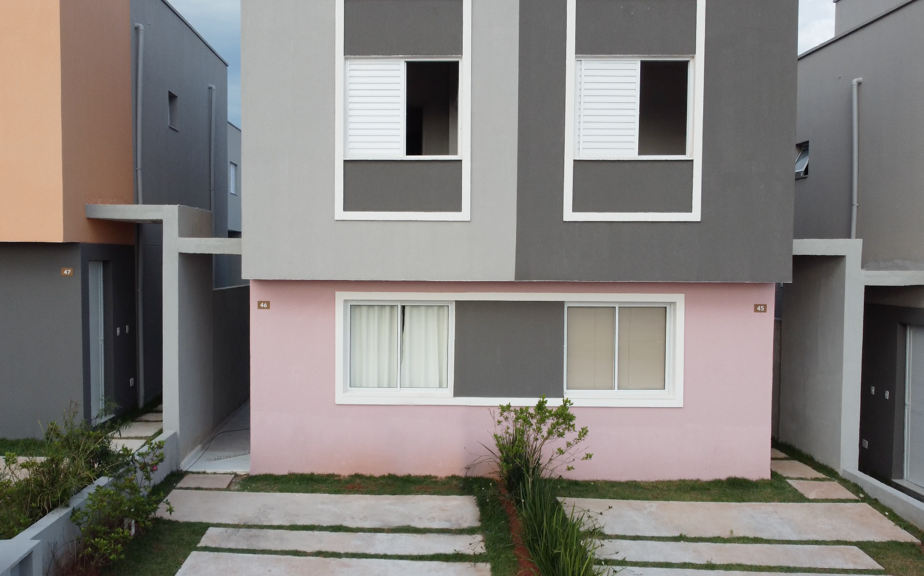 Uma casa rosa e cinza com muitas janelas