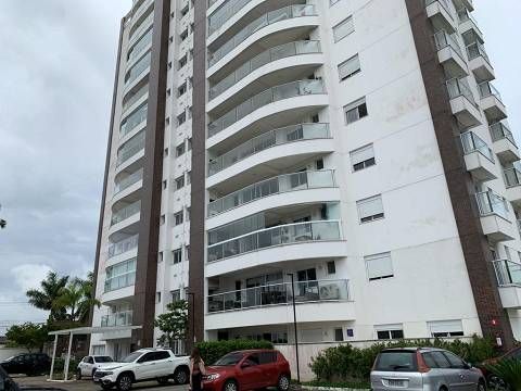 Um prédio alto com muitas janelas e carros estacionados na frente dele.