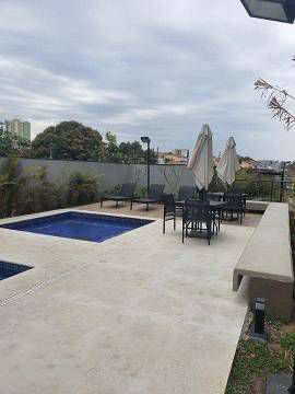 Uma grande piscina cercada por cadeiras, mesas e guarda-sóis.