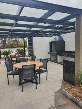 Um pátio com mesas e cadeiras e uma churrasqueira sob um dossel.