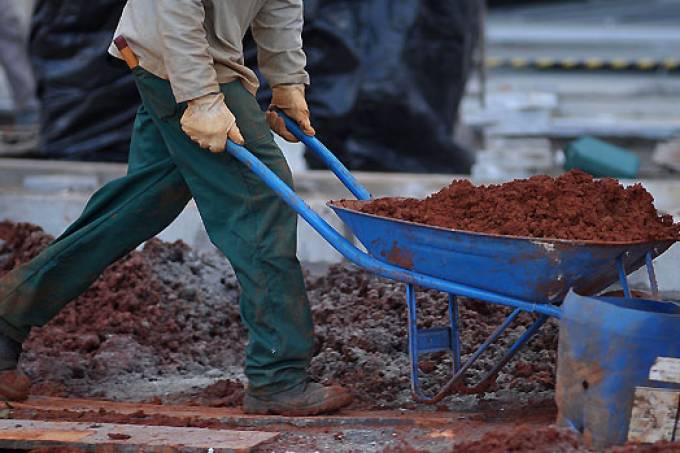 Um homem está empurrando um carrinho de mão cheio de terra.