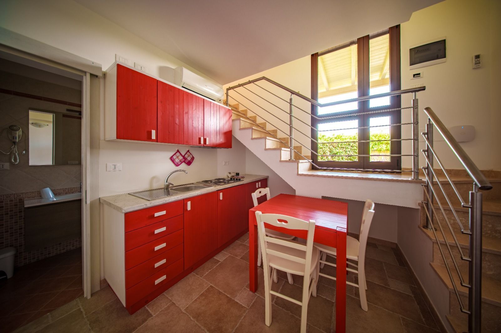Piccola cucina rossa con tavolo da pranzo e scala.