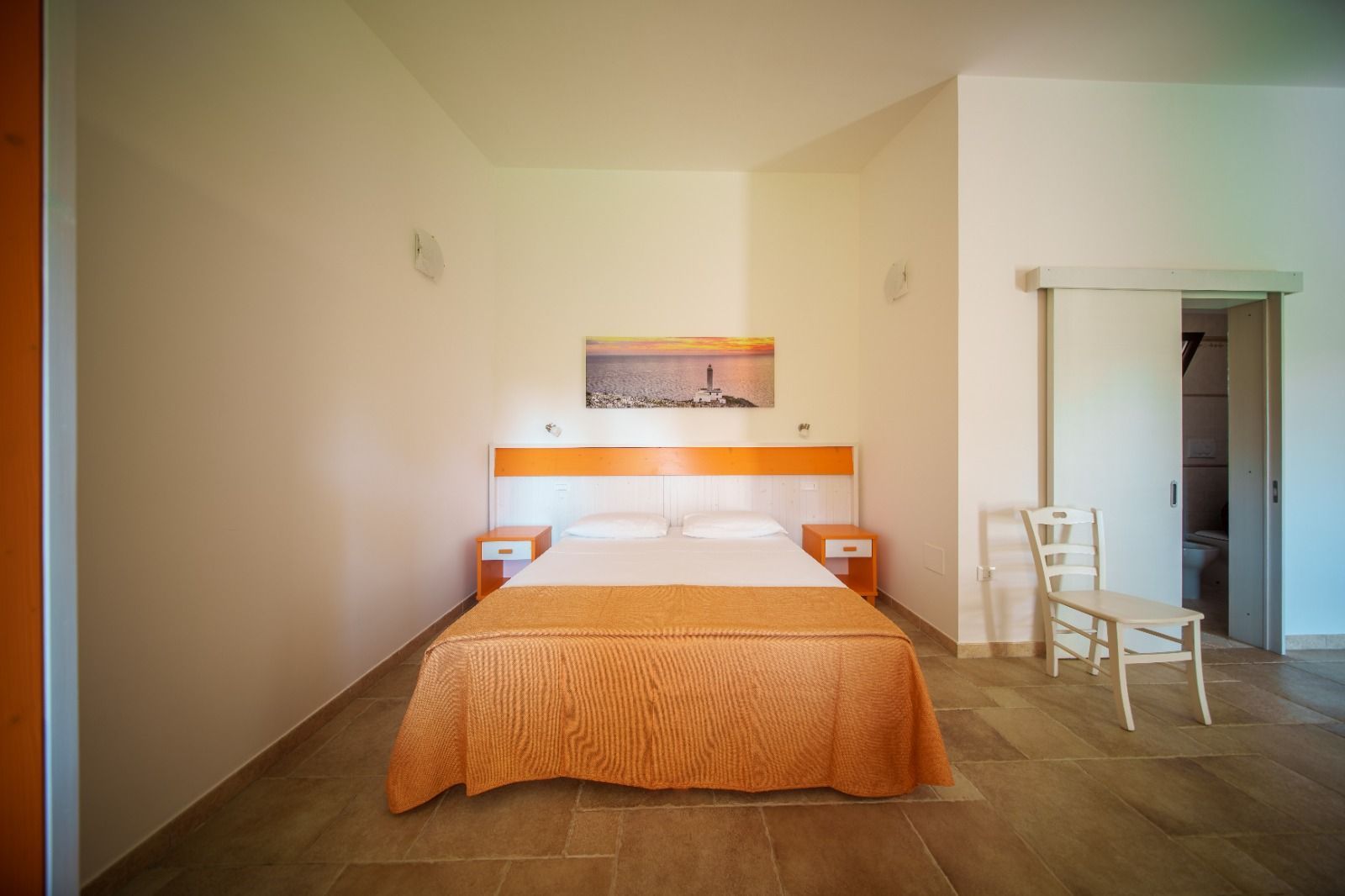 Camera da letto con letto, comodini e porta, decorata nei toni dell'arancione e del bianco.