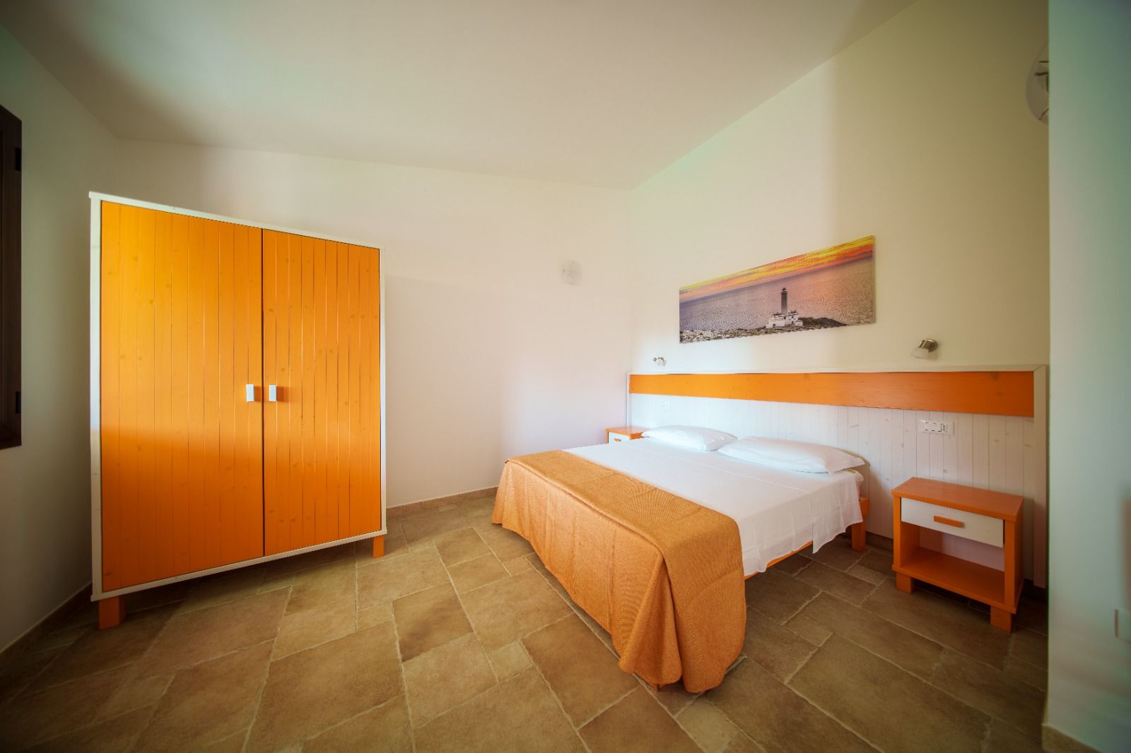 Una camera da letto con un armadio arancione acceso, un letto con un copriletto arancione e un comodino arancione abbinato.