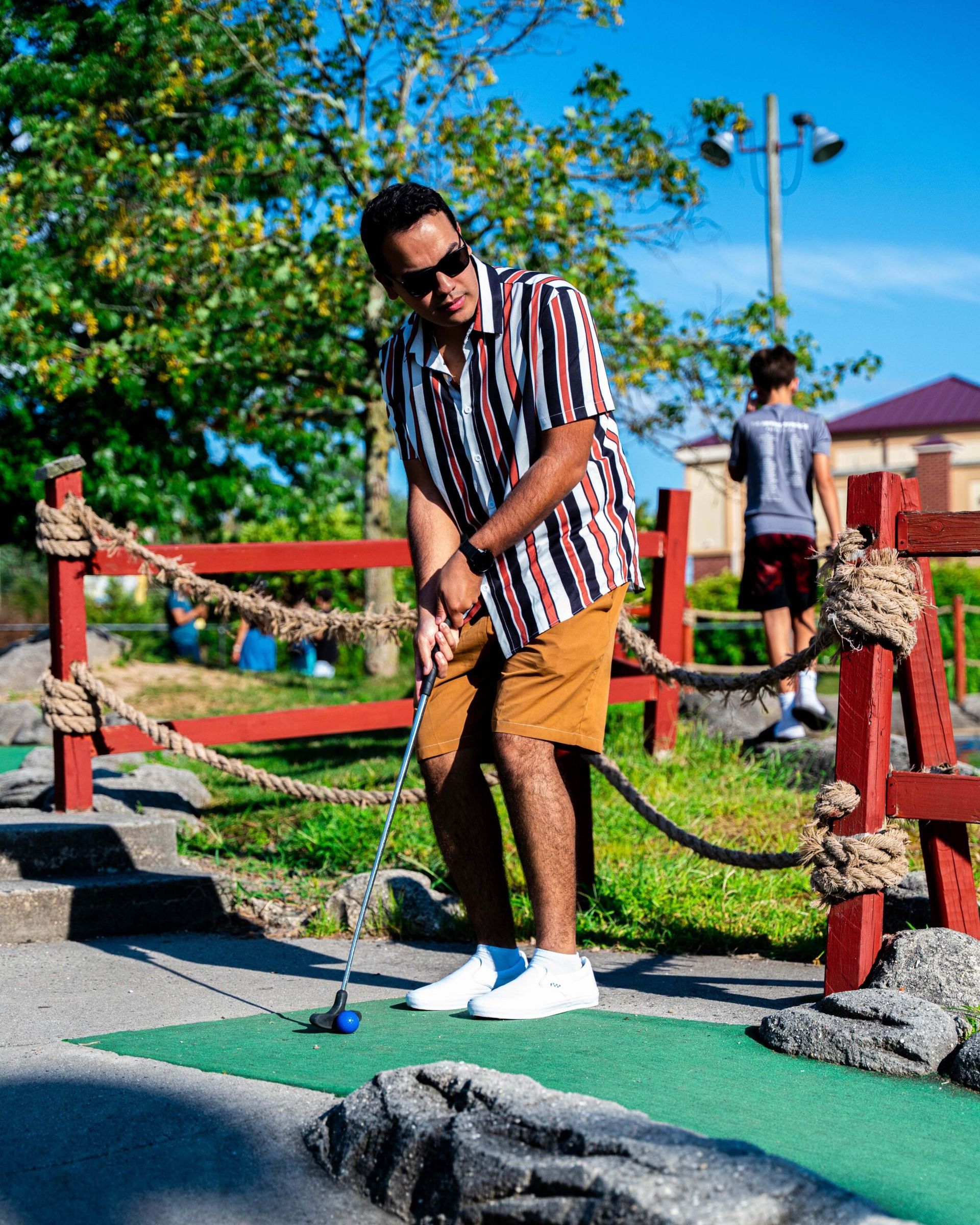 A man is playing a game of mini golf in a park.