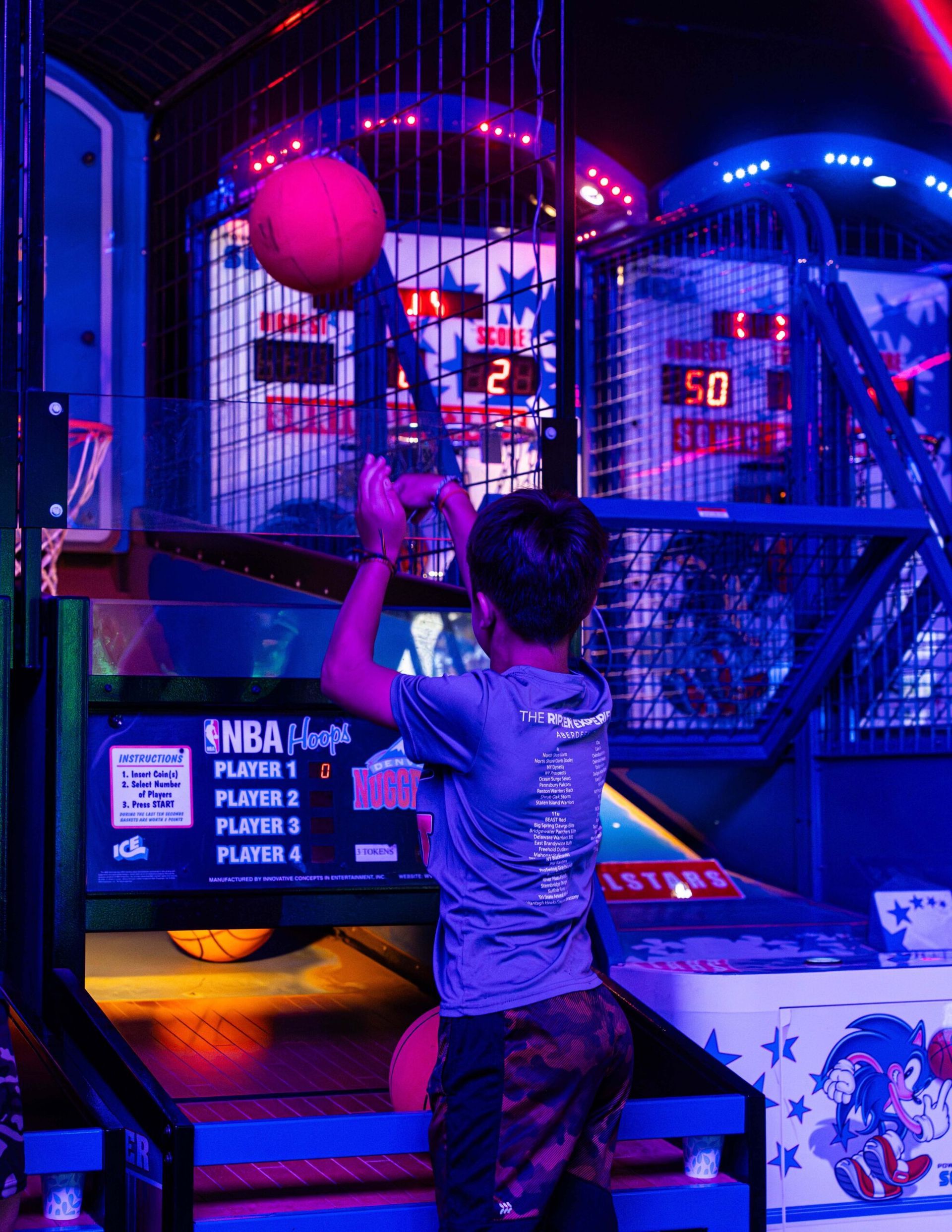 A young boy is playing a basketball game in an amusement park