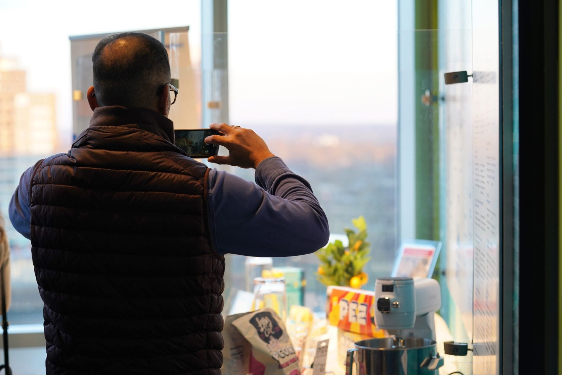Person takes a photo of a table with a phone. The table is by a window with a city view.