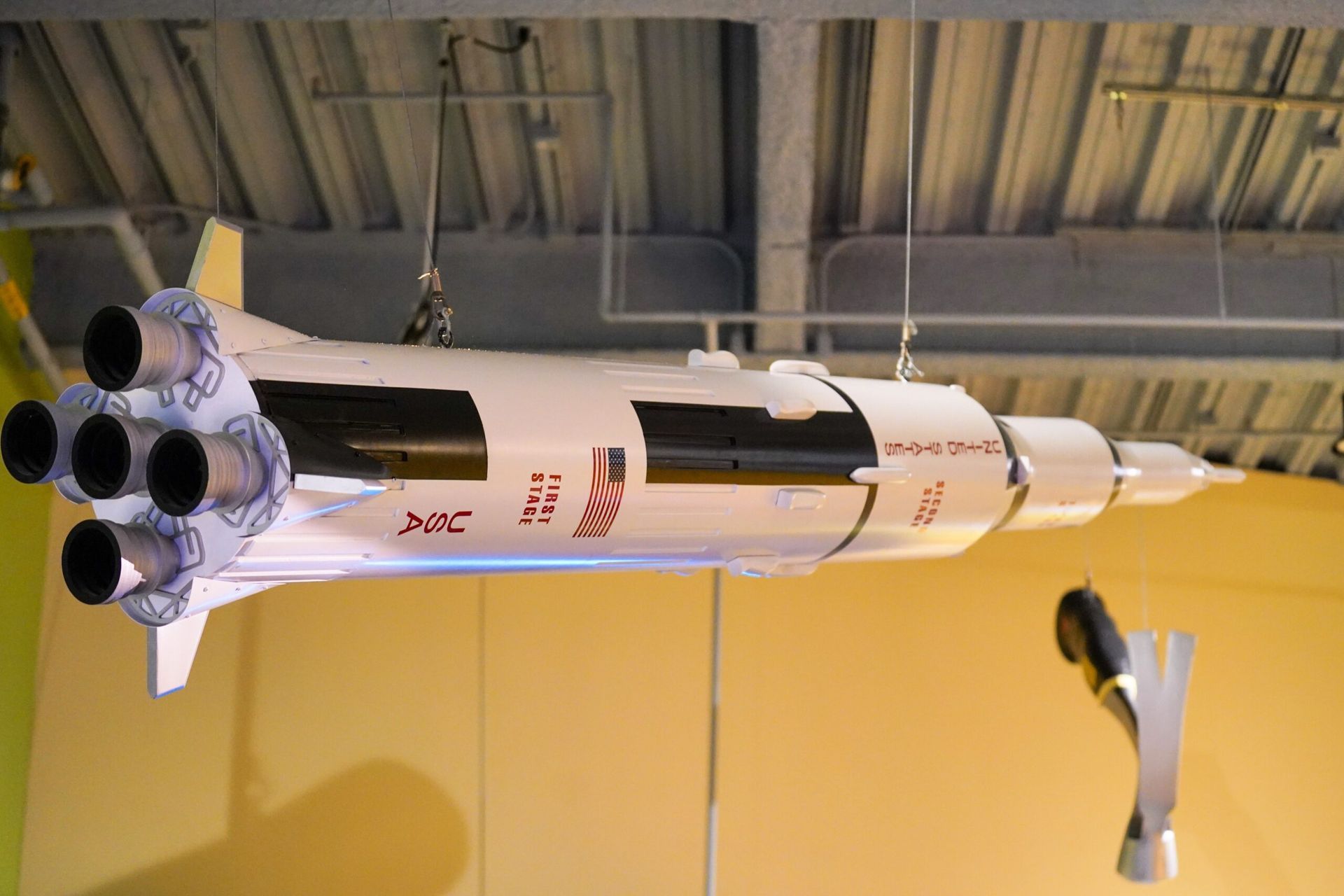Model of a white Saturn V rocket with black sections, hanging from the ceiling.