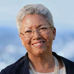 A portrait of Barbara Fernandez, Director, Public-Private Partnerships & Development at CONNSTEP, with gray hair and glasses smiling, wearing pearls and a navy jacket.