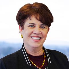 A portrait of Beatriz Gutierrez, President & CEO of CONNSTEP, smiling, wearing a black blazer and gold jewelry.