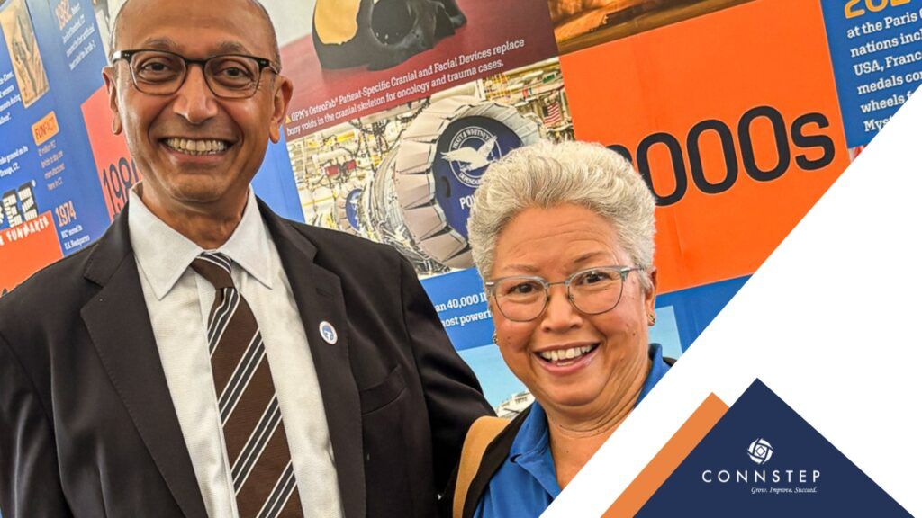 Two people smile, posing in front of a timeline display.