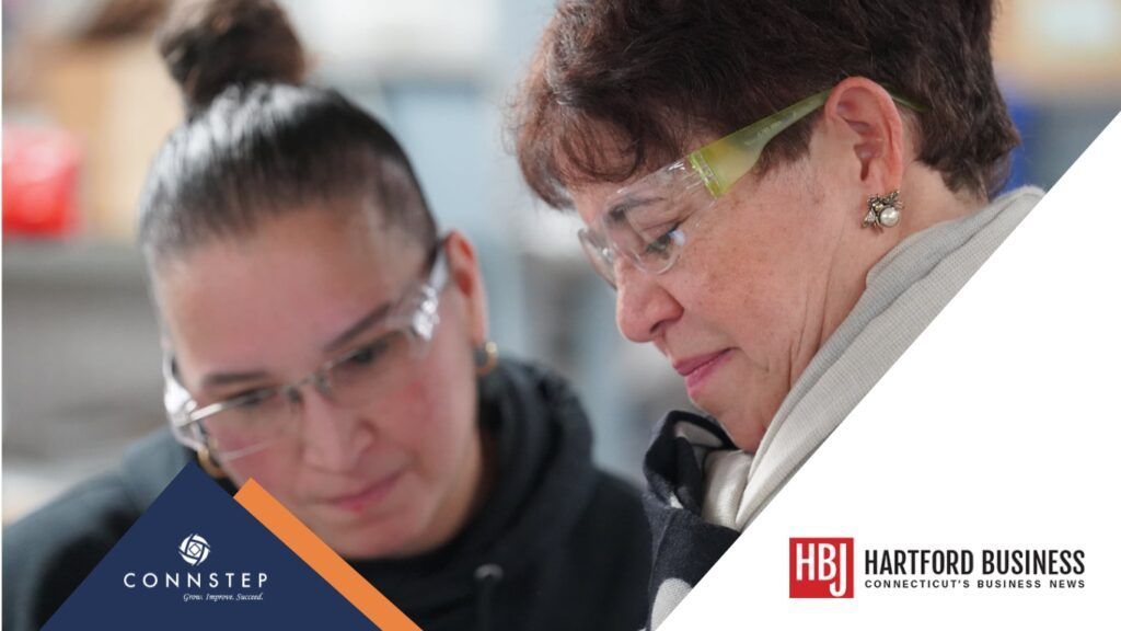 Two women wearing safety glasses looking closely at something, possibly a project.